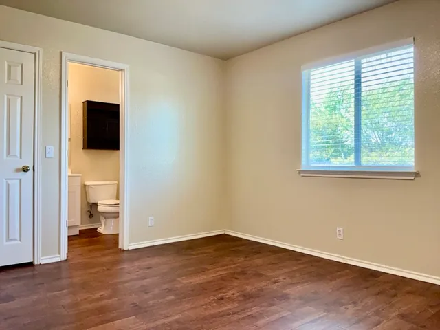 a view of an empty room with a window and wooden floor
