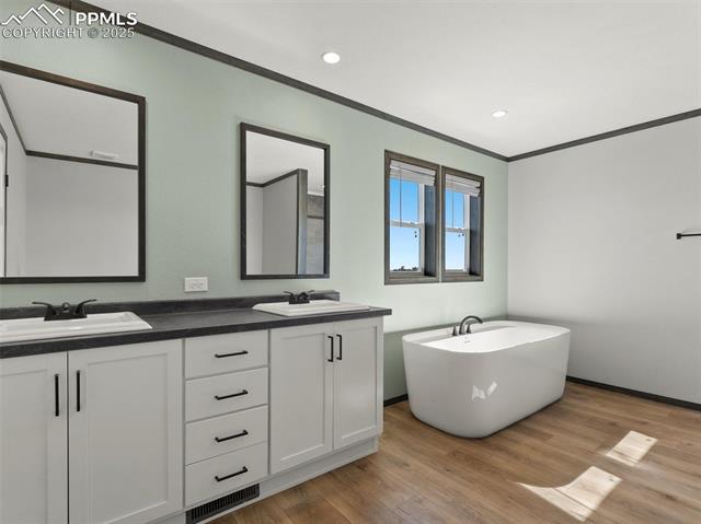 22843 Handle Road Calhan, CO 80808 - Photo 10 of 47 Bathroom with a freestanding bath, double vanity, crown molding, light wood-style flooring, and recessed lighting