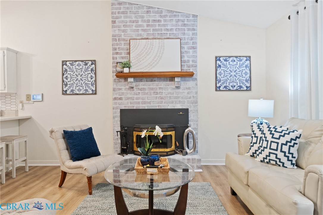 Living room featuring lofted ceiling, light wood-type flooring, and a brick fireplace