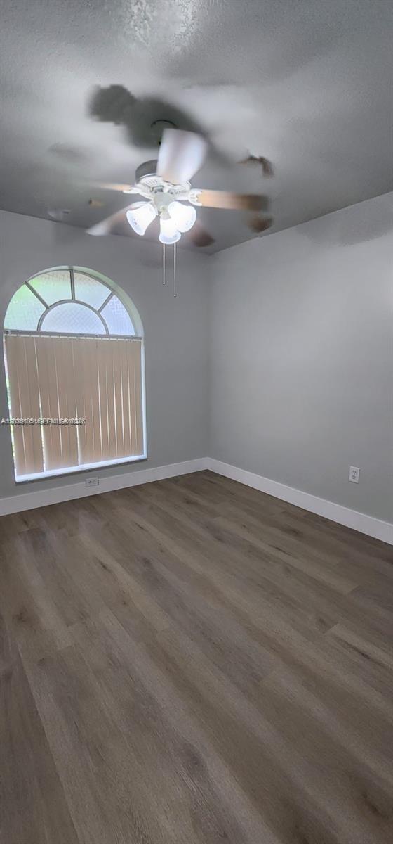 14817 Southwest 180th Street Miami, FL 33187 - Photo 6 of 15 an empty room with wooden floor chandelier fan and windows