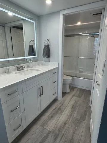 a bathroom with a double vanity sink a toilet and a large mirror