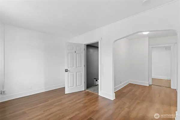an empty room with wooden floor & windows