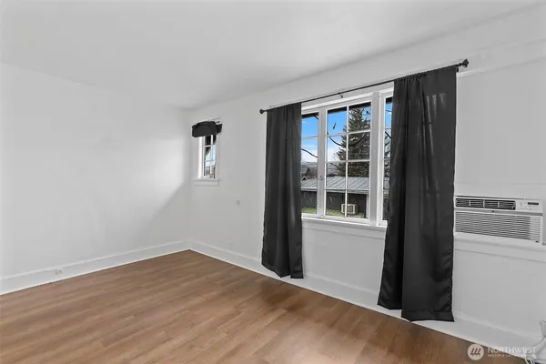 a view of an empty room with wooden floor and a window