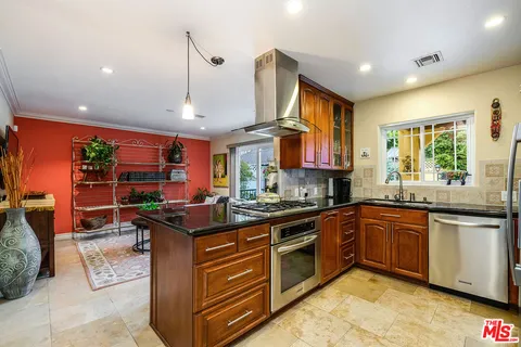 a large kitchen with stainless steel appliances granite countertop a stove a sink dishwasher a refrigerator and a counter space