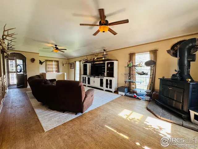 a living room with couches a fireplace and a dining table with wooden floor