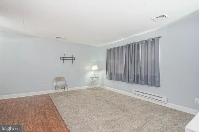 a view of an empty room with window and wooden floor