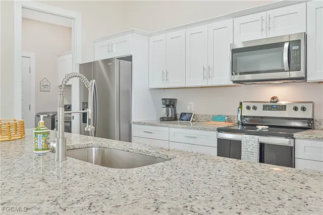 a kitchen with stainless steel appliances granite countertop a sink a stove top oven and refrigerator