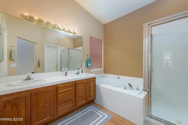 a bathroom with a tub double vanity sink and mirror
