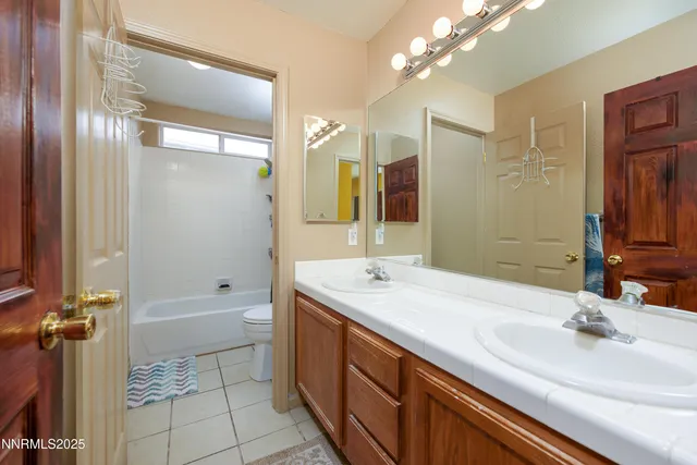 a bathroom with a sink double vanity granite tub shower and a mirror