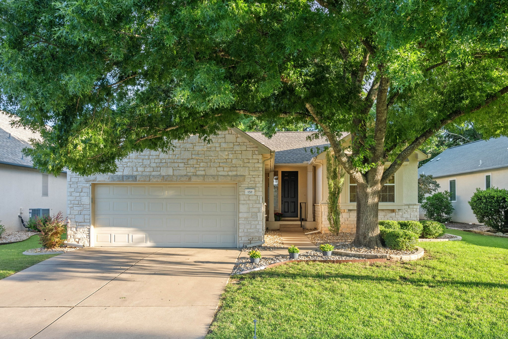 137 Trail Rider Way Georgetown, TX 78633 - Photo 1 of 29 A welcoming stone facade home with an attached garage, nestled under a grand shade tree.