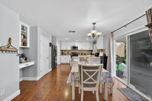 a kitchen with stainless steel appliances kitchen island granite countertop a refrigerator a stove a microwave oven a dining table and chairs with wooden floor