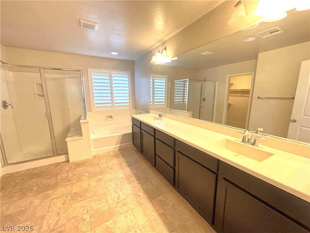 121 Elm Reed Avenue Las Vegas, NV 89113 - Photo 20 of 30 The primary bathroom provides abundant space for two with separate sinks, a full-sized mirror, and a shower alongside a tub.