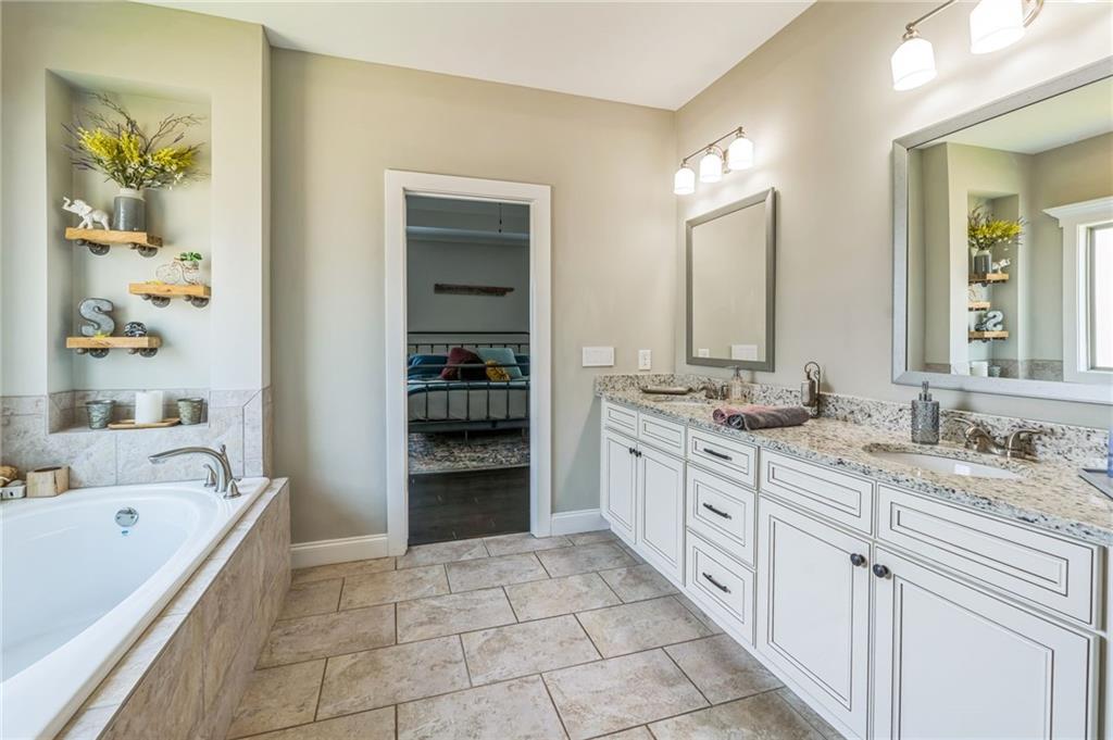 1621 Highland Creek Drive Monroe, GA 30656 - Photo 21 of 54 a spacious bathroom with a granite countertop sink a mirror a bathtub and a shower