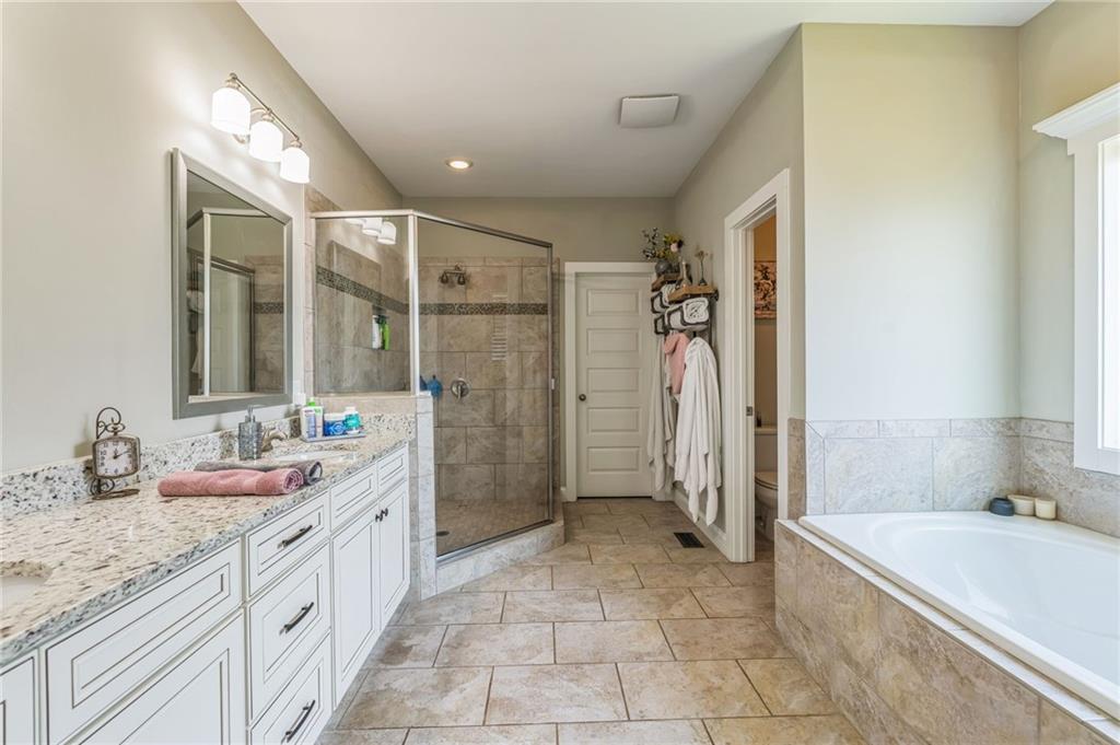 1621 Highland Creek Drive Monroe, GA 30656 - Photo 22 of 54 a spacious bathroom with a granite countertop sink a mirror a bathtub and next to a window