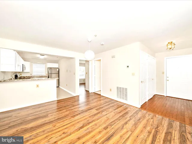 a view of kitchen and empty room with wooden floor