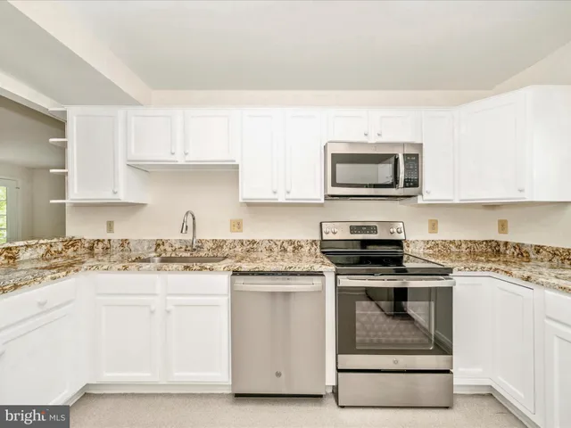 a kitchen with granite countertop a stove top oven microwave and cabinets
