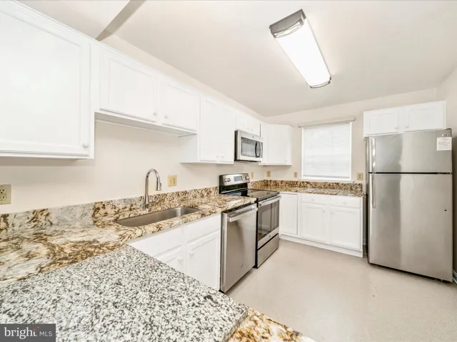 a kitchen with granite countertop white cabinets and white appliances