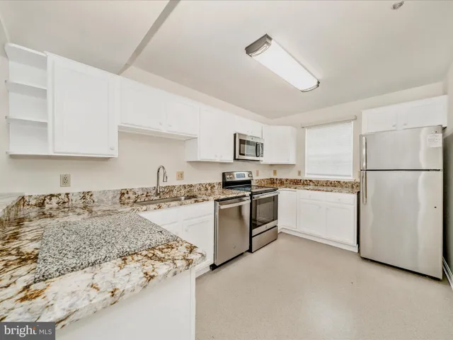 a kitchen with granite countertop white cabinets and white appliances