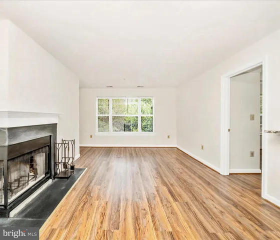 an empty room with wooden floor fireplace and windows