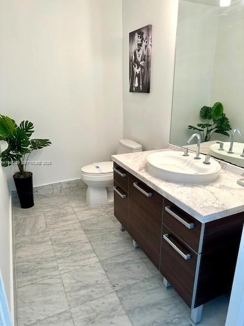 253 Northeast 2nd Street, Unit 421 Miami, FL 33132 - Photo 7 of 15 a bathroom with a granite countertop sink a toilet and a mirror