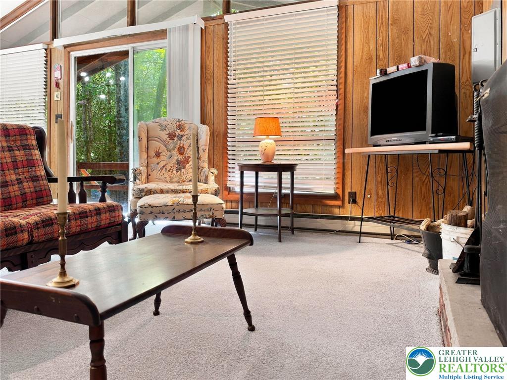 116 Aspen Road Albrightsville, PA 18210 - Photo 21 of 33 Rich wood paneling and sliding doors opening to the outdoors define this rustic living area.