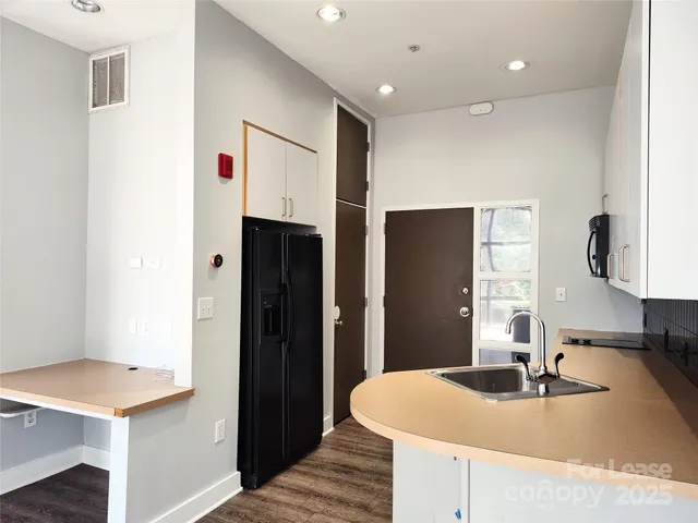 a kitchen with stainless steel appliances kitchen island a sink dishwasher a refrigerator and a stove with wooden floor