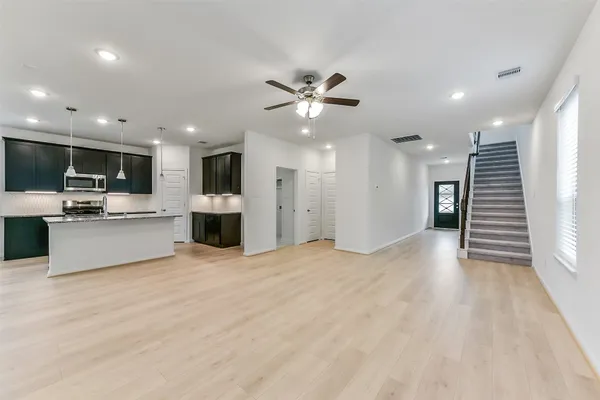 a large kitchen with stainless steel appliances a large counter top a stove and a refrigerator