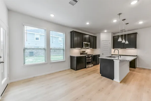 a kitchen with stainless steel appliances granite countertop a stove a sink and a microwave
