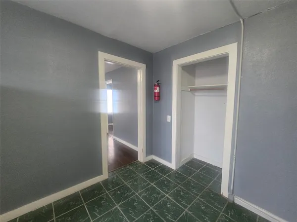 an empty room with wooden floor and windows with curtains