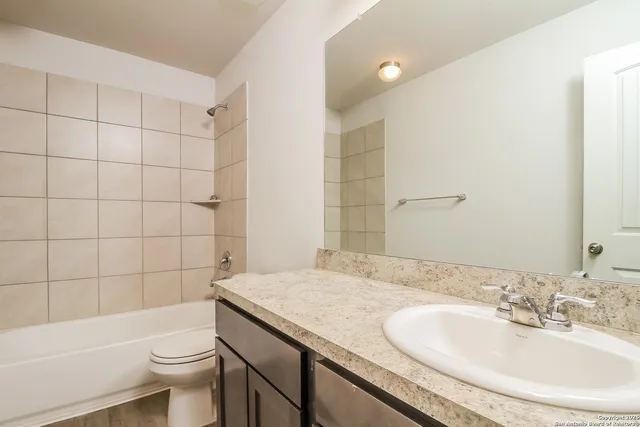 a bathroom with a granite countertop sink a toilet a mirror and shower