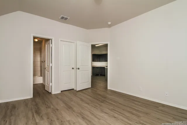an empty room with wooden floor & closet and windows