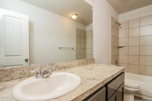 a bathroom with a granite countertop sink a toilet and a mirror