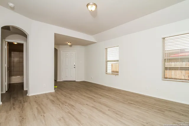 an empty room with wooden floor and windows