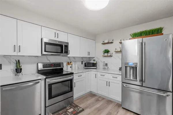 a kitchen with a refrigerator a microwave a sink and cabinets