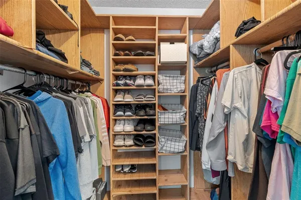 a view of walk in closet with clothes and shoes