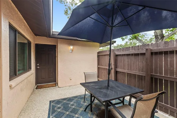 a backyard of a house with table and chairs under an umbrella