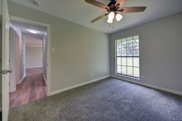 an empty room with chandelier fan and windows