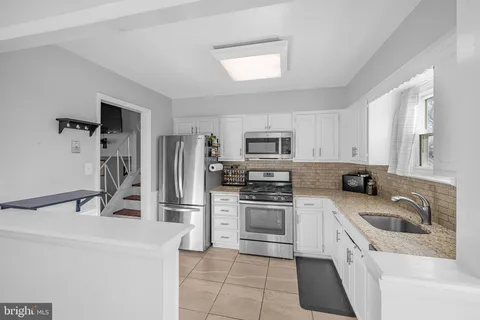 a kitchen with stainless steel appliances granite countertop a sink dishwasher a refrigerator and a stove
