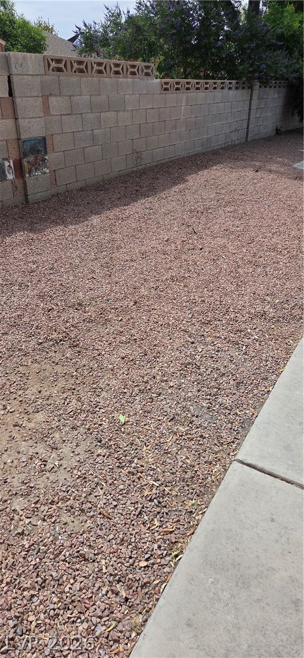 571 Roxella Lane, Unit C Las Vegas, NV 89110 - Photo 2 of 14 This yard features a durable block fence with decorative openings, providing a structured outdoor space.