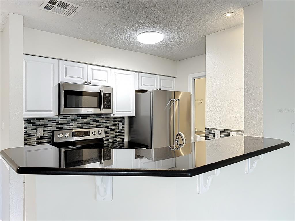 232 Afton Square, Unit 201 Altamonte Springs, FL 32714 - Photo 23 of 54 a kitchen with kitchen island a stove and a microwave