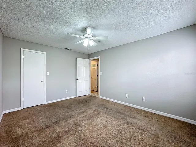 an empty room with wooden floor chandelier fan and windows
