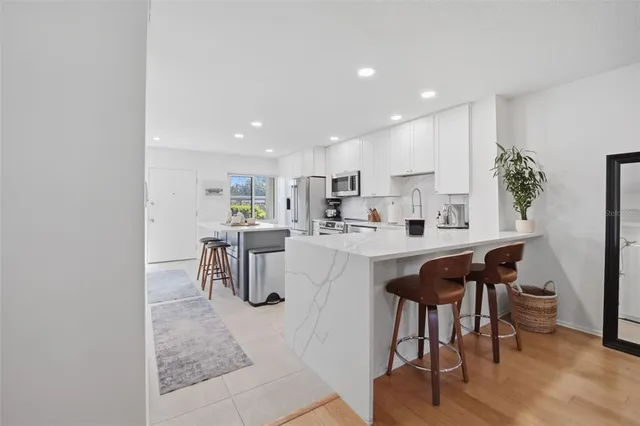 a kitchen with stainless steel appliances kitchen island granite countertop a table chairs and a refrigerator