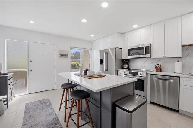 a kitchen with stainless steel appliances a stove a refrigerator a sink a dining table and chairs