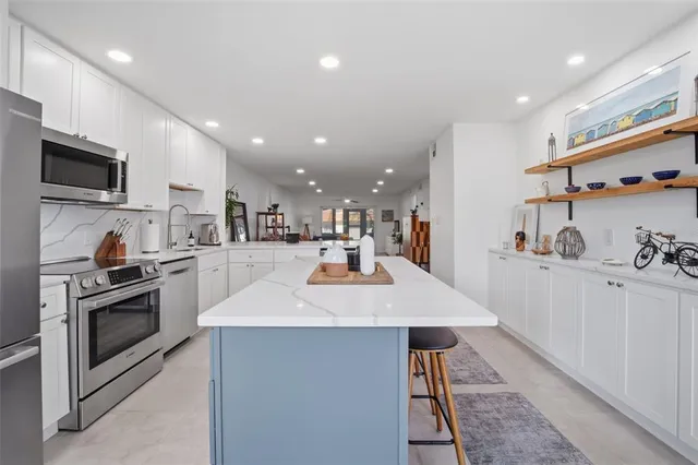 a kitchen with stainless steel appliances kitchen island granite countertop a sink and stove top oven with wooden floor