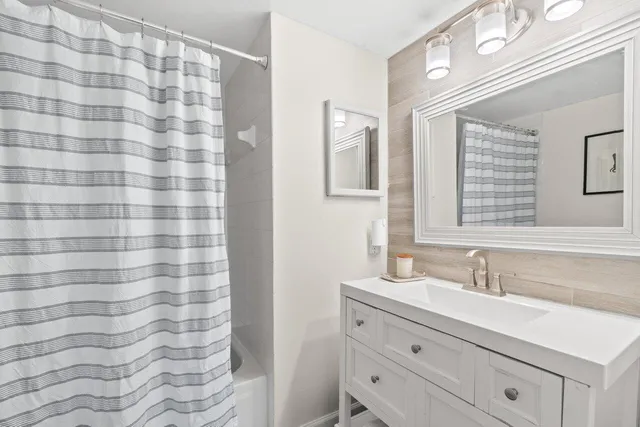 a bathroom with a sink a mirror a vanity and a shower