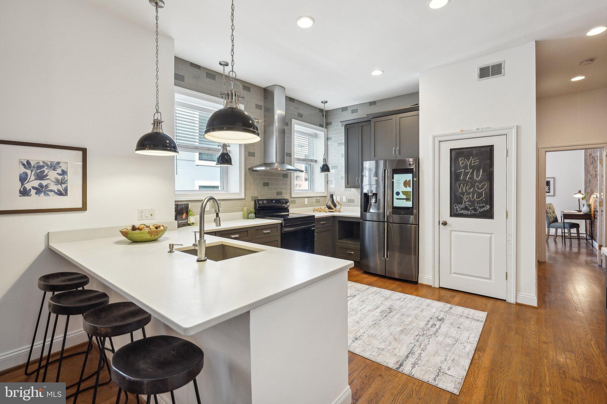 77 U Street Northwest Washington, DC 20001 - Photo 5 of 34 a kitchen with a sink a stove and chairs with wooden floor