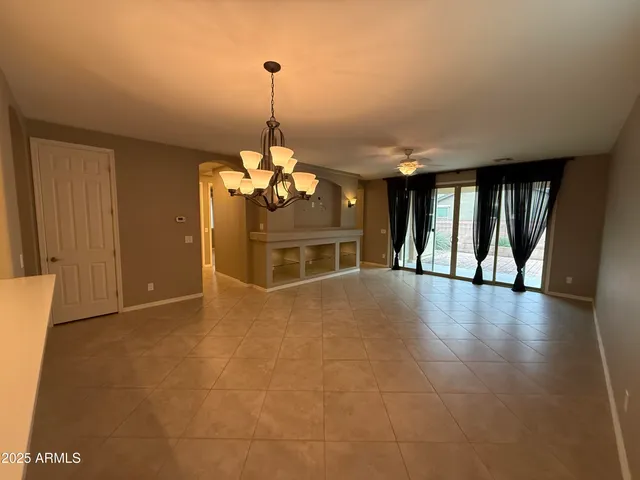 a view of a livingroom with a fireplace a chandelier and windows