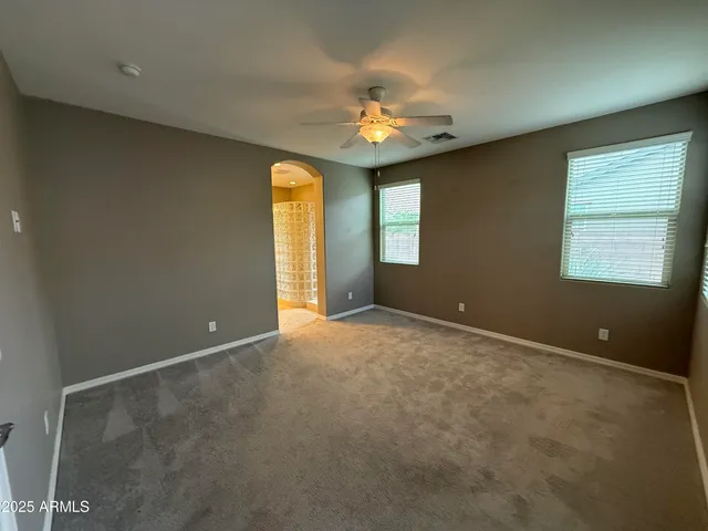an empty room with a chandelier fan and windows