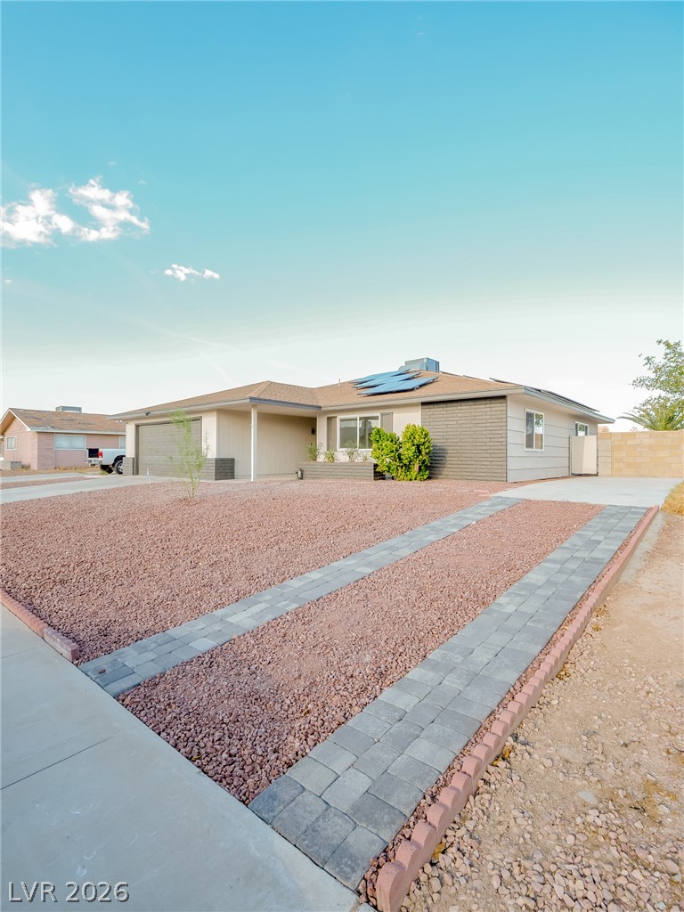 321 Lakehurst Road Las Vegas, NV 89145 - Photo 4 of 33 A single-story exterior features desert landscaping and solar panel installations.