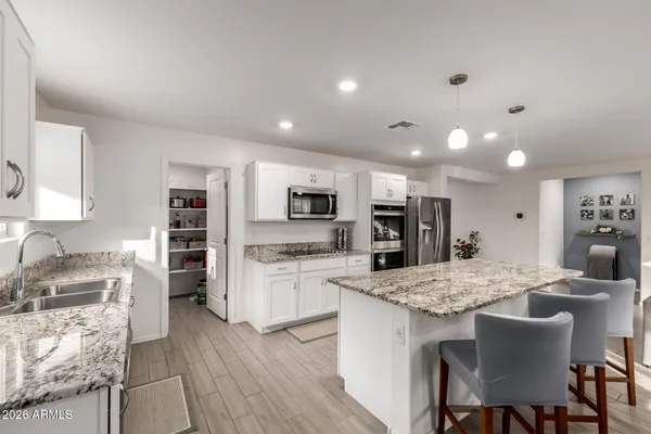 a kitchen with stainless steel appliances granite countertop a stove top oven a sink dishwasher a dining table and chairs